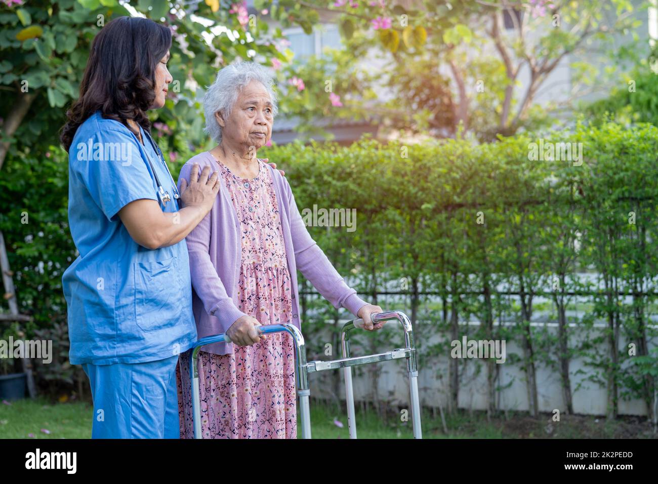 Aiuto del medico e cura Asian anziani o anziani donna vecchia uso walker con la salute forte mentre camminando al parco in felice vacanza fresca. Foto Stock