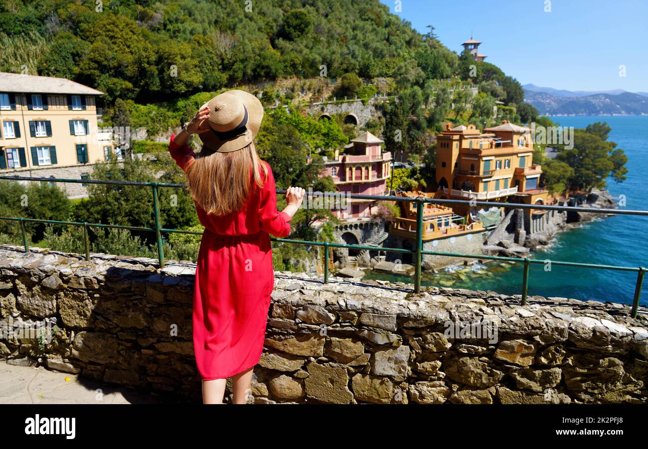 Giovane ragazza alla moda in abito rosso che guarda la baia di Portofino, Italia. Stagione primaverile. Foto Stock