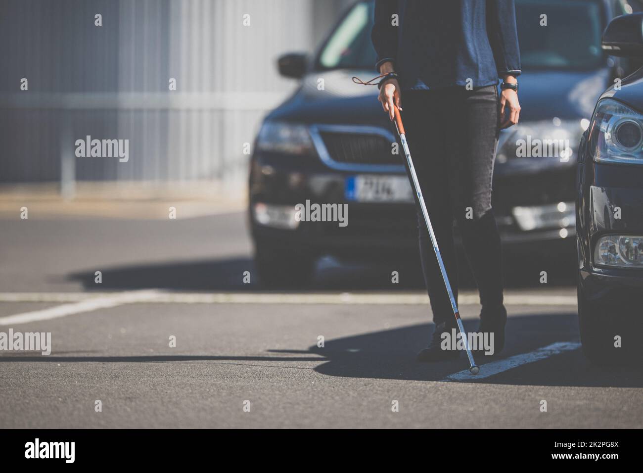 Donna cieca che cammina per le strade della città, utilizzando la sua canna bianca per navigare meglio lo spazio urbano e per raggiungere la sua destinazione in modo sicuro Foto Stock