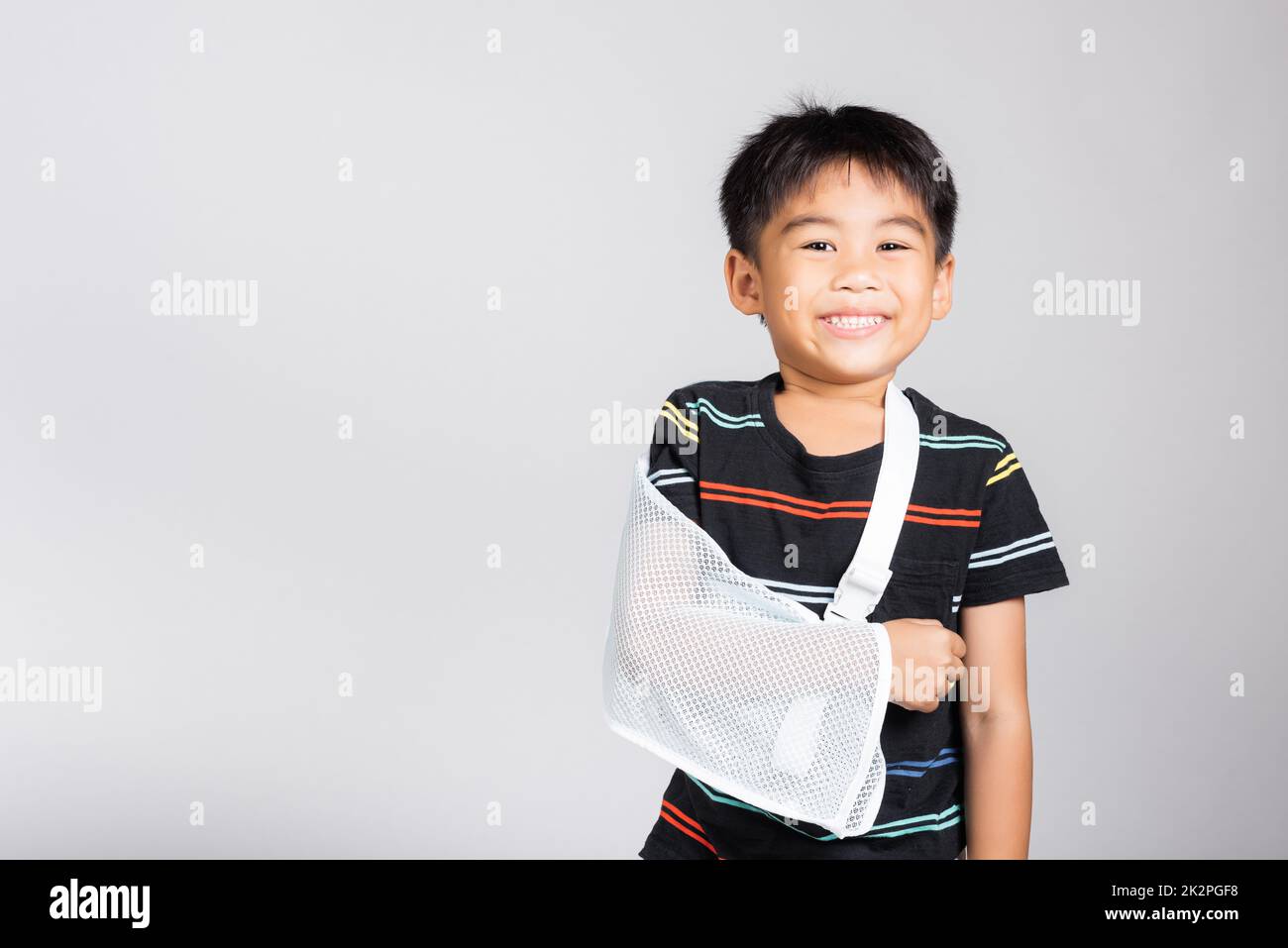 Piccolo carino ragazzo 5-6 anni osso della mano rotto da incidente con stecca del braccio in studio sparato isolato Foto Stock