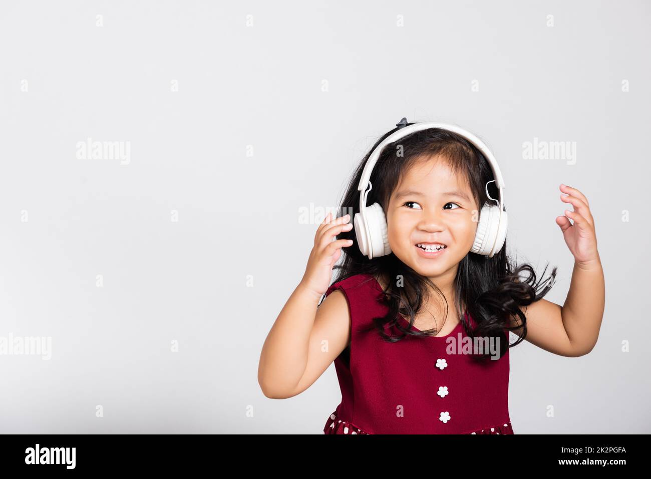 Piccola ragazza carina di 3-4 anni ascolta la musica con cuffie wireless Foto Stock