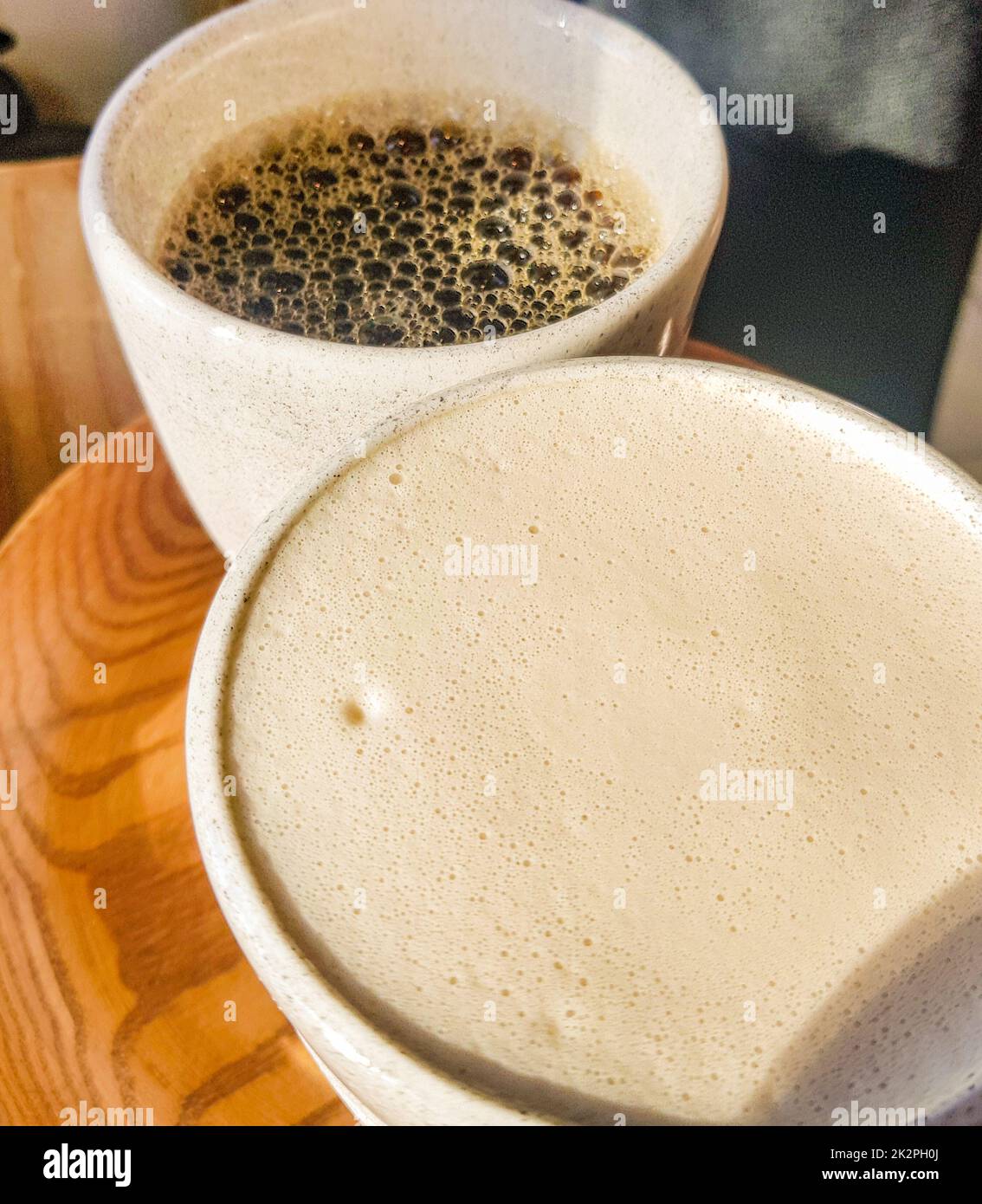 Cappuccino con fragrante schiuma di latte e americano nero su un vassoio di legno Vista dall'alto. Caffè per due. Delizioso caffè appena fatto per colazione nel caffè Foto Stock