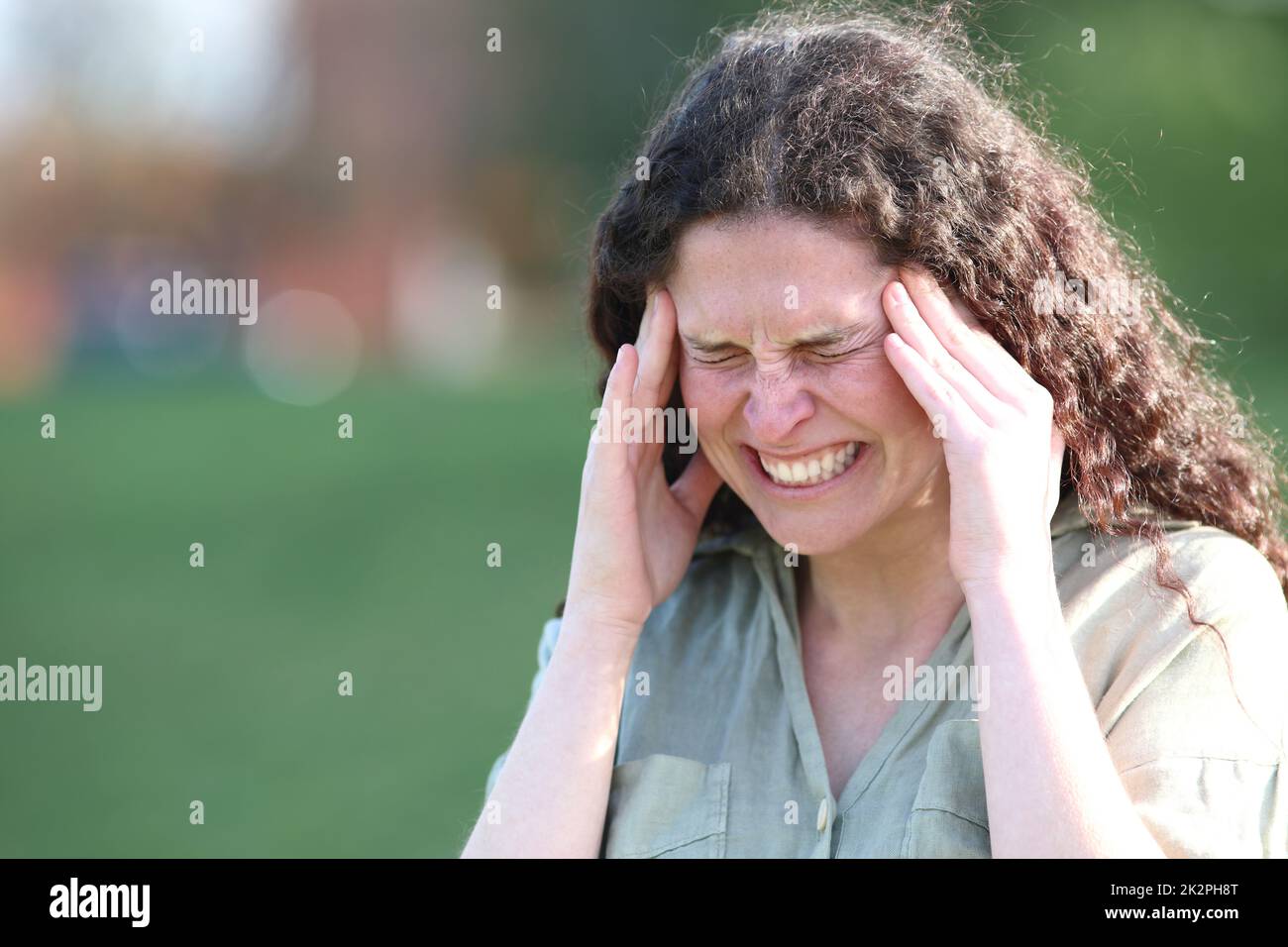 Donna che lamenta l'attacco di emicrania sofferenza in un parco Foto Stock