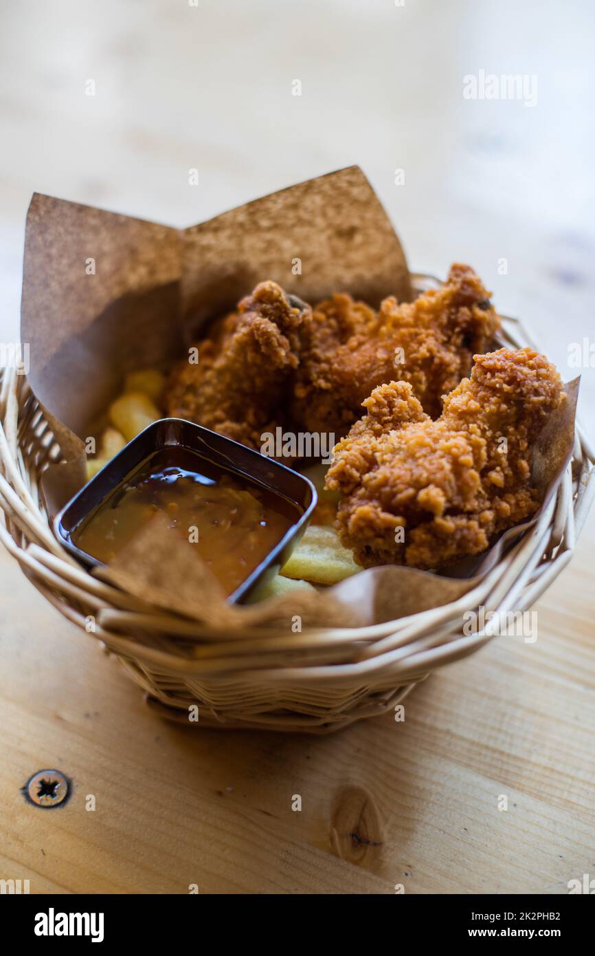 Ali di pollo in un cestino, con patatine fritte e salsa Foto Stock