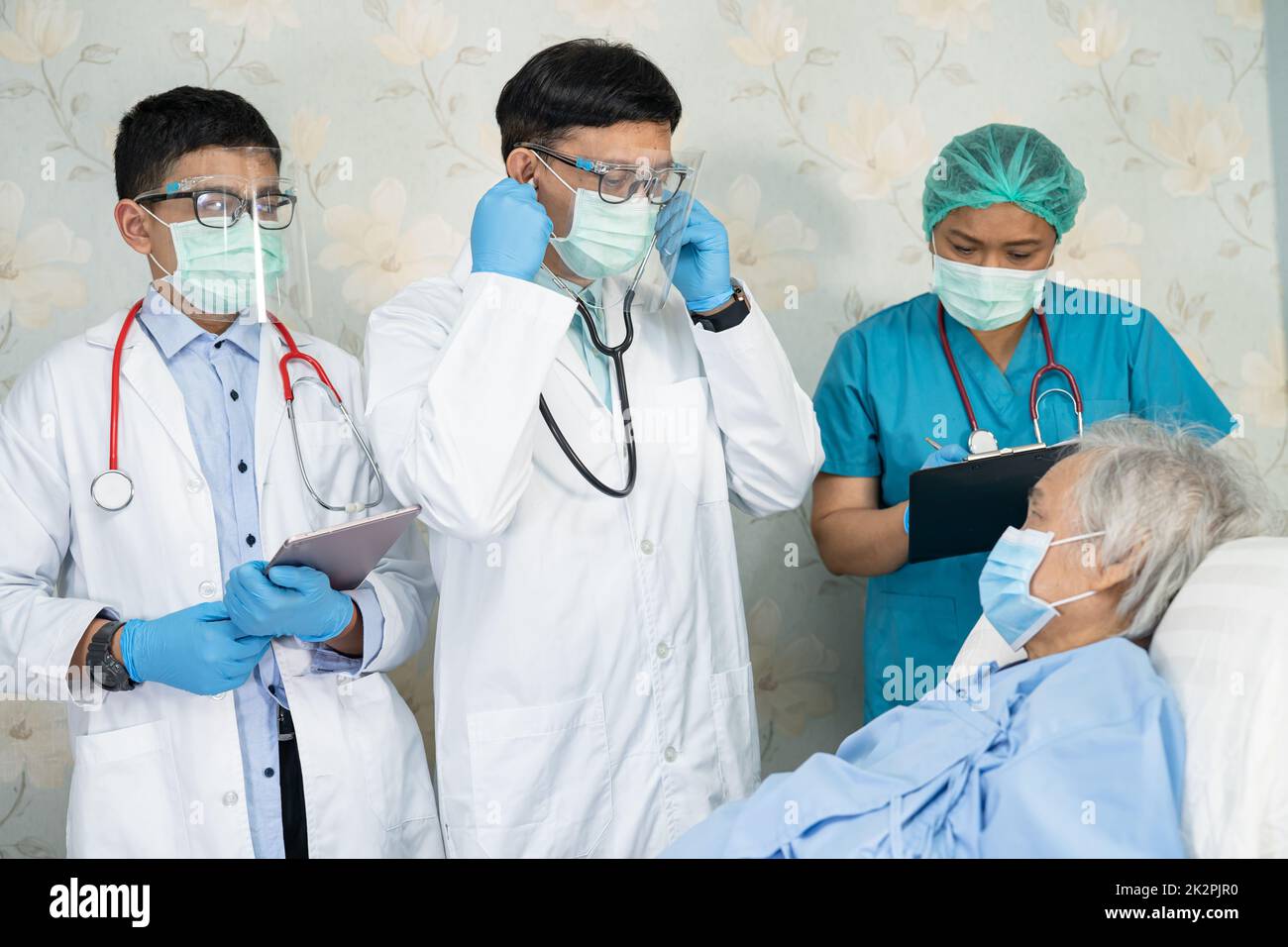 Team medico asiatico controllare la vecchia donna anziana paziente per la malattia alla motivazione nuovo normale per trattare l'infezione Covid-19 Coronavirus al reparto ospedaliero. Foto Stock