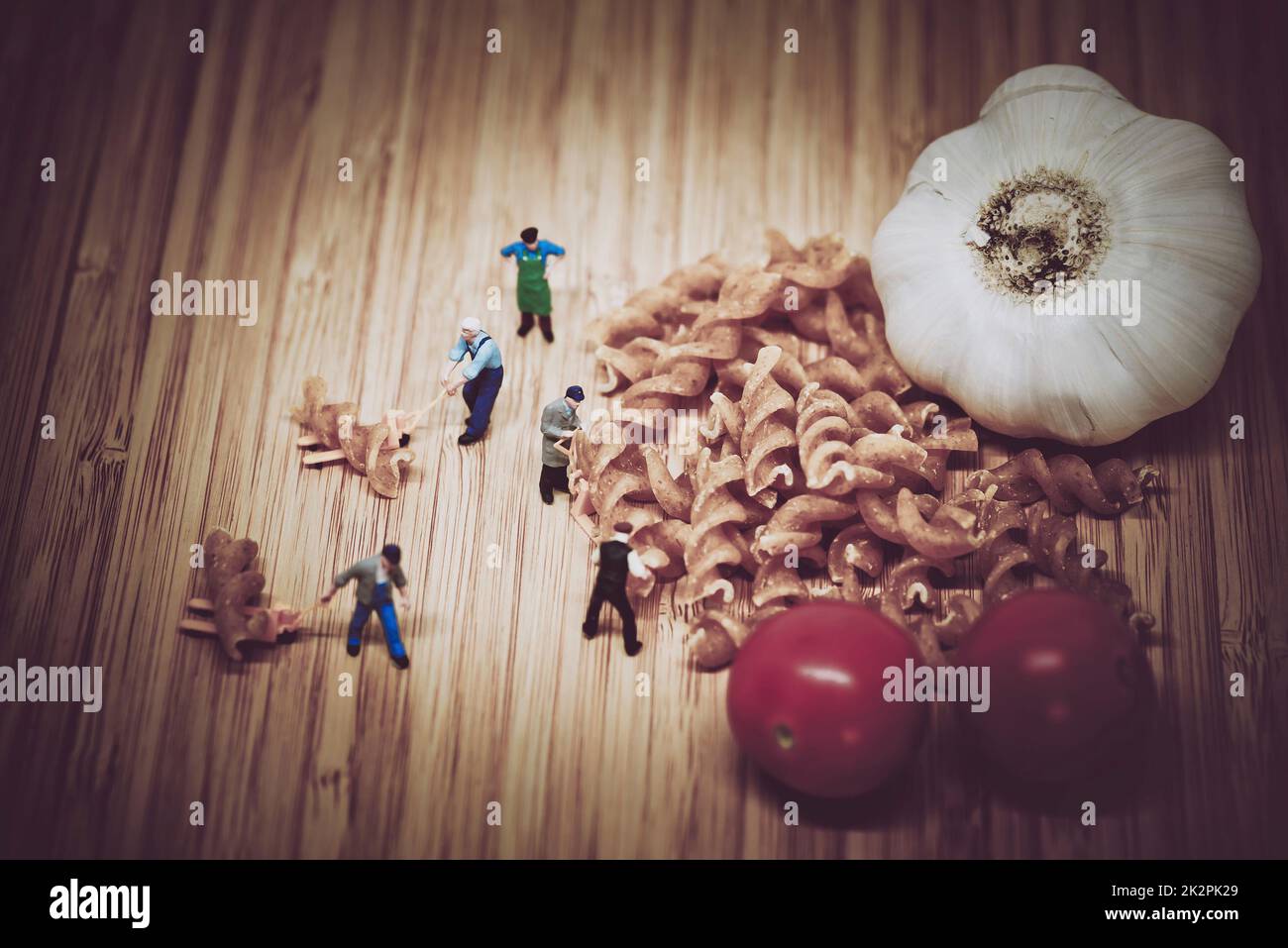 Le persone in miniatura raccolgono gli ingredienti per cucinare la pasta. Tono colore sintonizzato. Foto Stock