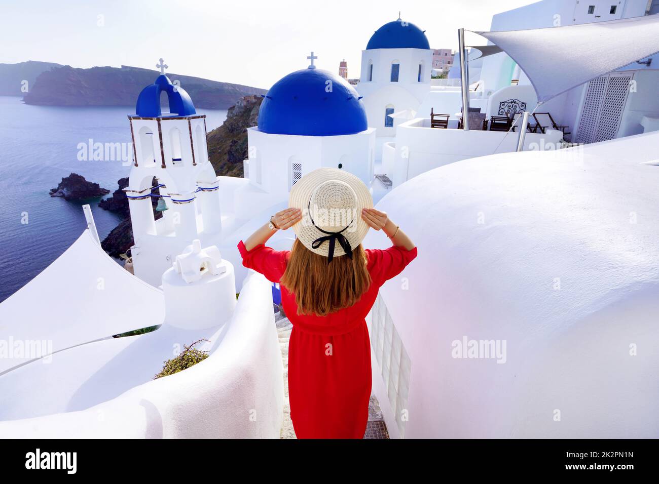 Vacanze a Santorini. Vista posteriore della donna viaggiatore scende scale nel tradizionale villaggio di Oia con cupole blu churces e con case sull'isola di Santorini. Foto Stock