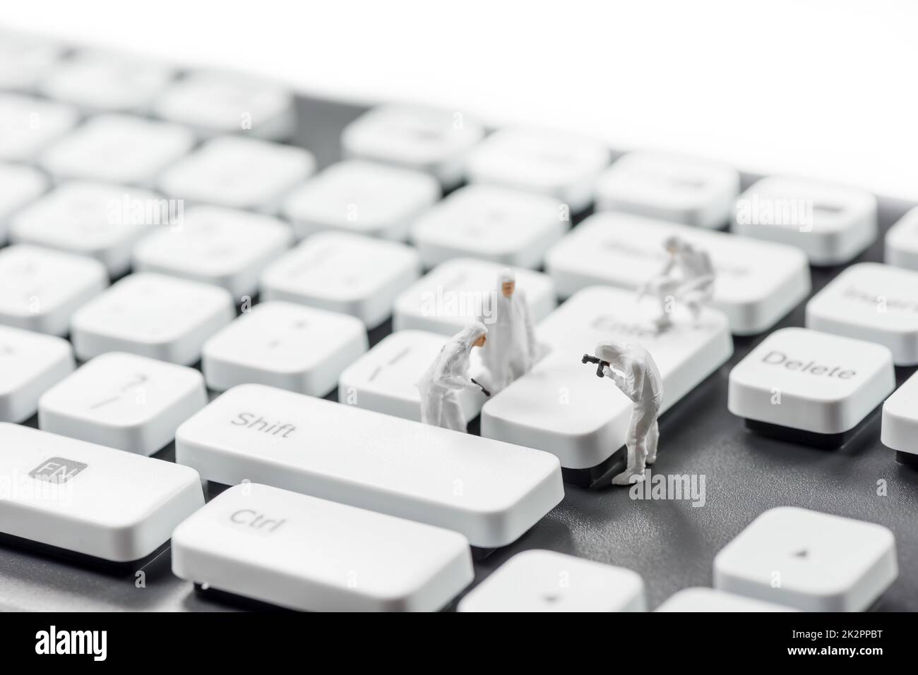 Gruppo di criminali in miniatura che ispezionano la tastiera del computer. Concetto di criminalità informatica Foto Stock