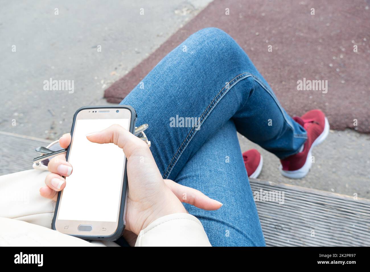 La ragazza tiene in mano uno smartphone con uno schermo bianco per il layout o la pubblicità sul telefono display.A mezzi di comunicazione, comunicazione e Internet.Banner, cartellone, poster, playbill Foto Stock