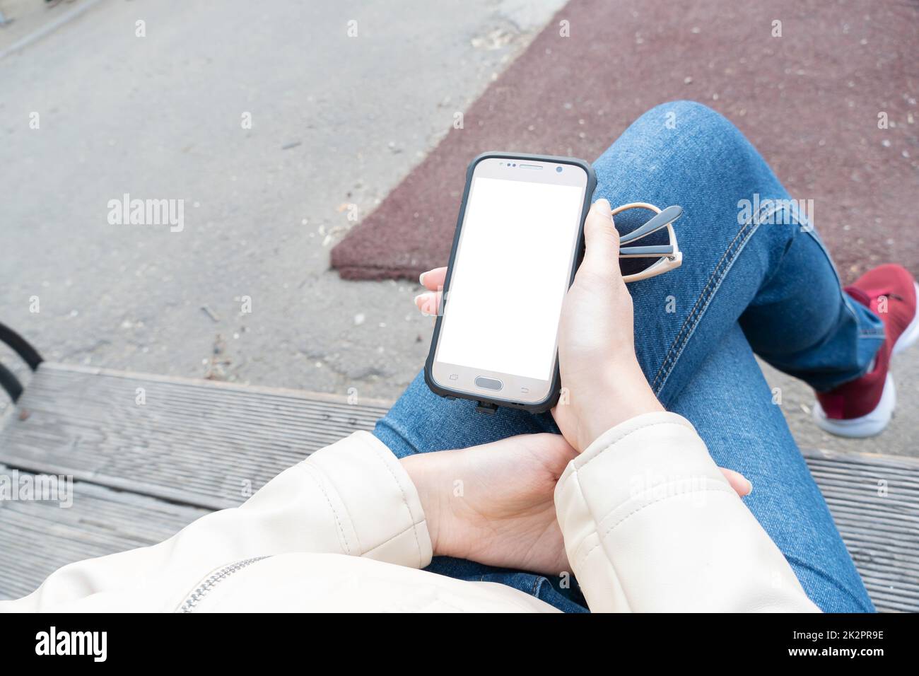 La ragazza tiene in mano uno smartphone con uno schermo bianco per il layout o la pubblicità sul telefono display.A mezzi di comunicazione, comunicazione e Internet.Banner, cartellone, poster, playbill Foto Stock