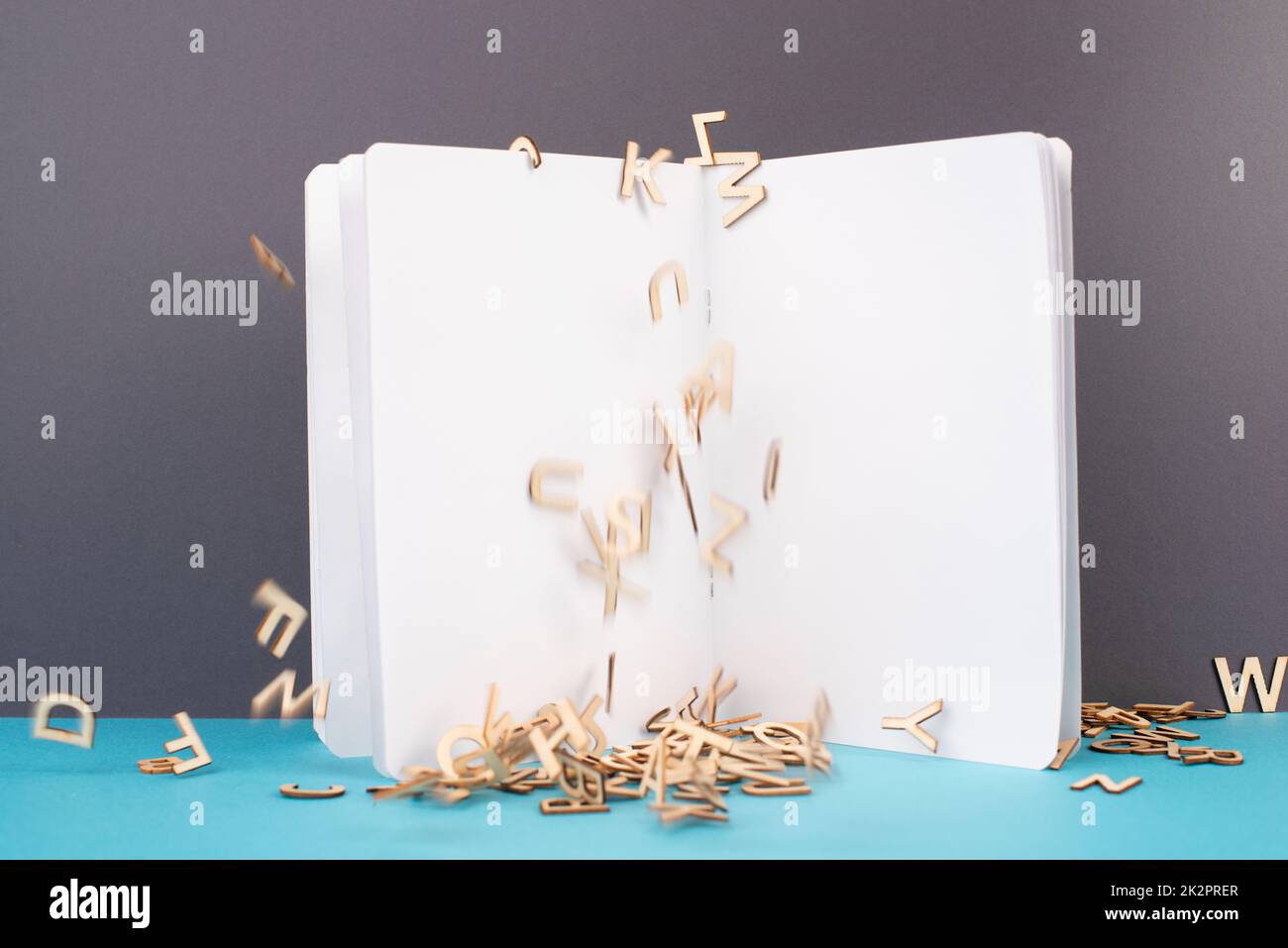 Aprire la pagina del libro bianco, le lettere di legno che cadono giù, la scuola e il concetto di istruzione, lo spazio della copia per il testo Foto Stock