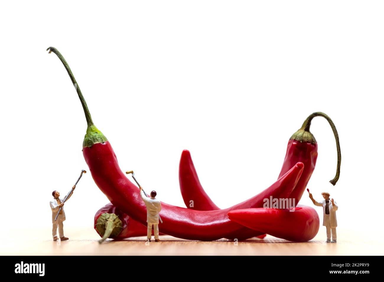 Pittori in miniatura che colorano peperoncini rossi. Foto macro Foto Stock