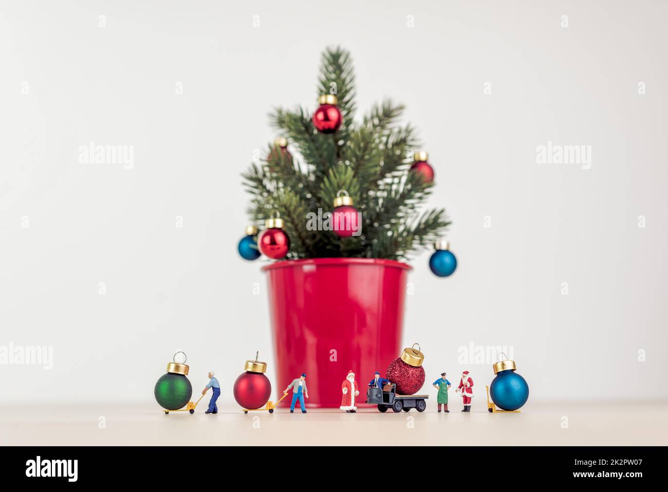 Persone in miniatura che decorano l'albero di Natale gigante Foto Stock