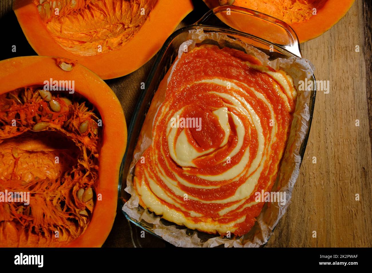 Cheesecake fatta in casa con torta di zucca e un pezzo di zucca. Dessert all'arancia. immagine verticale. posiziona per il testo su sfondo di legno Foto Stock