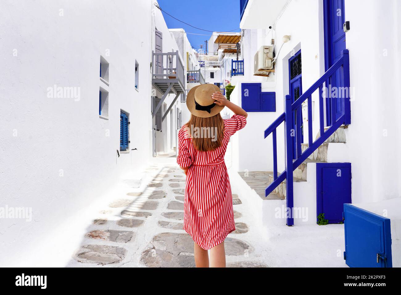 La ragazza del viaggiatore cammina attraverso i vicoli nella pittoresca città di Mykonos in Grecia Foto Stock