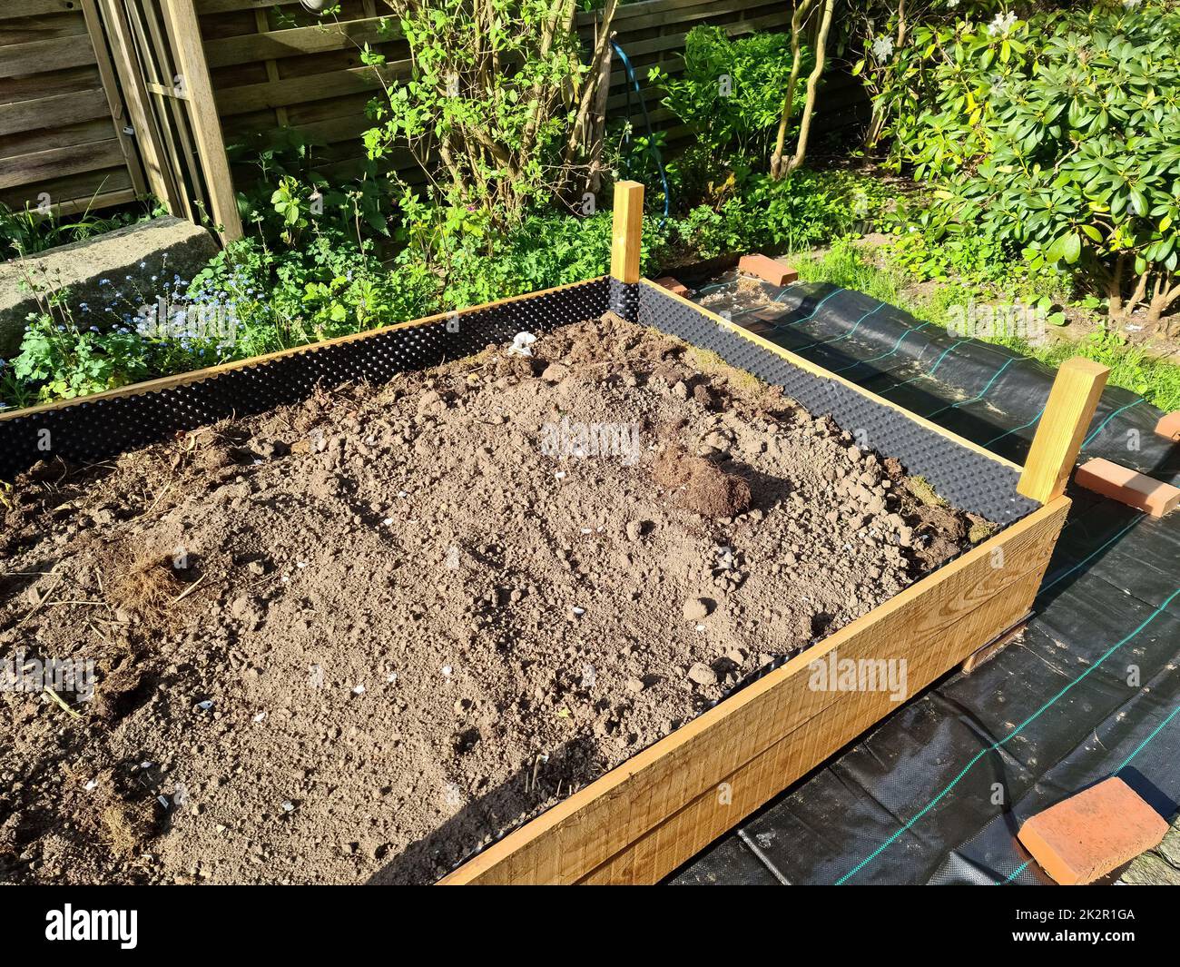 Letto di erbe rialzato durante la costruzione in un giardino tedesco. Foto Stock