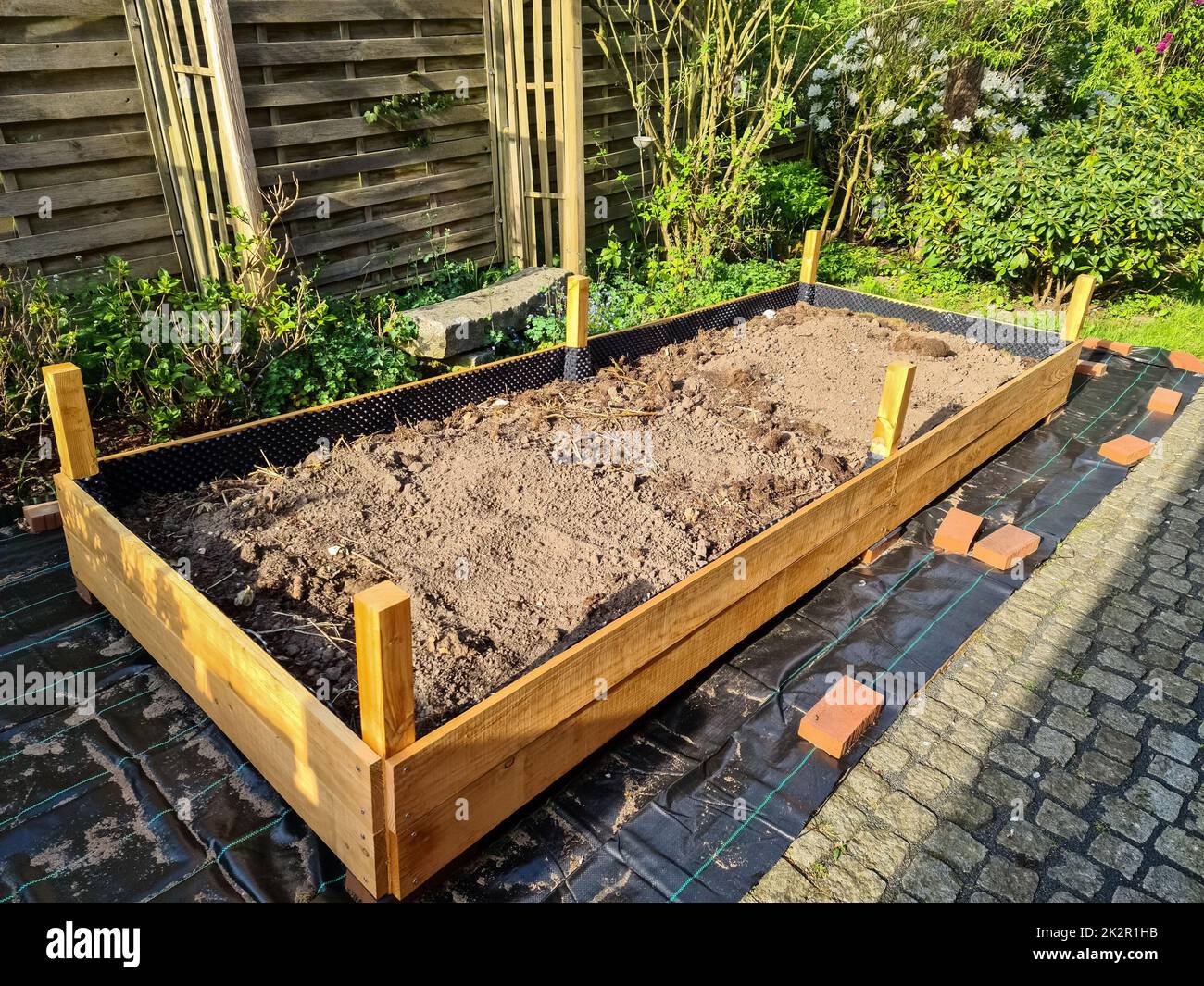Letto di erbe rialzato durante la costruzione in un giardino tedesco. Foto Stock