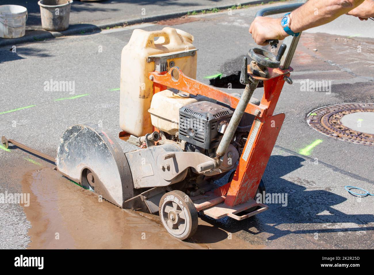 L'operatore stradale taglia il calcestruzzo con una macchina per il taglio del calcestruzzo Foto Stock