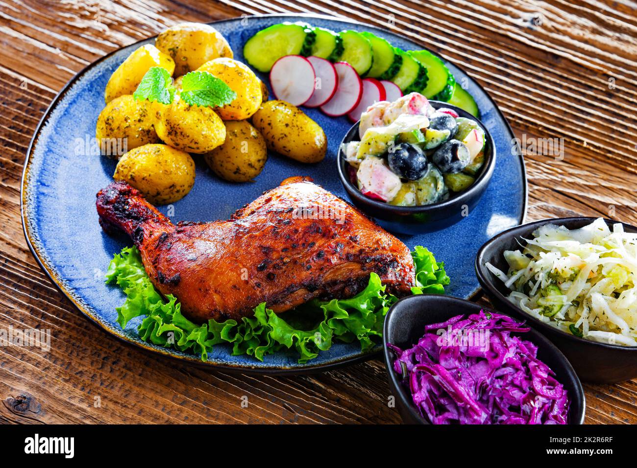 Coscia di pollo al forno con patate e insalate di verdure Foto Stock
