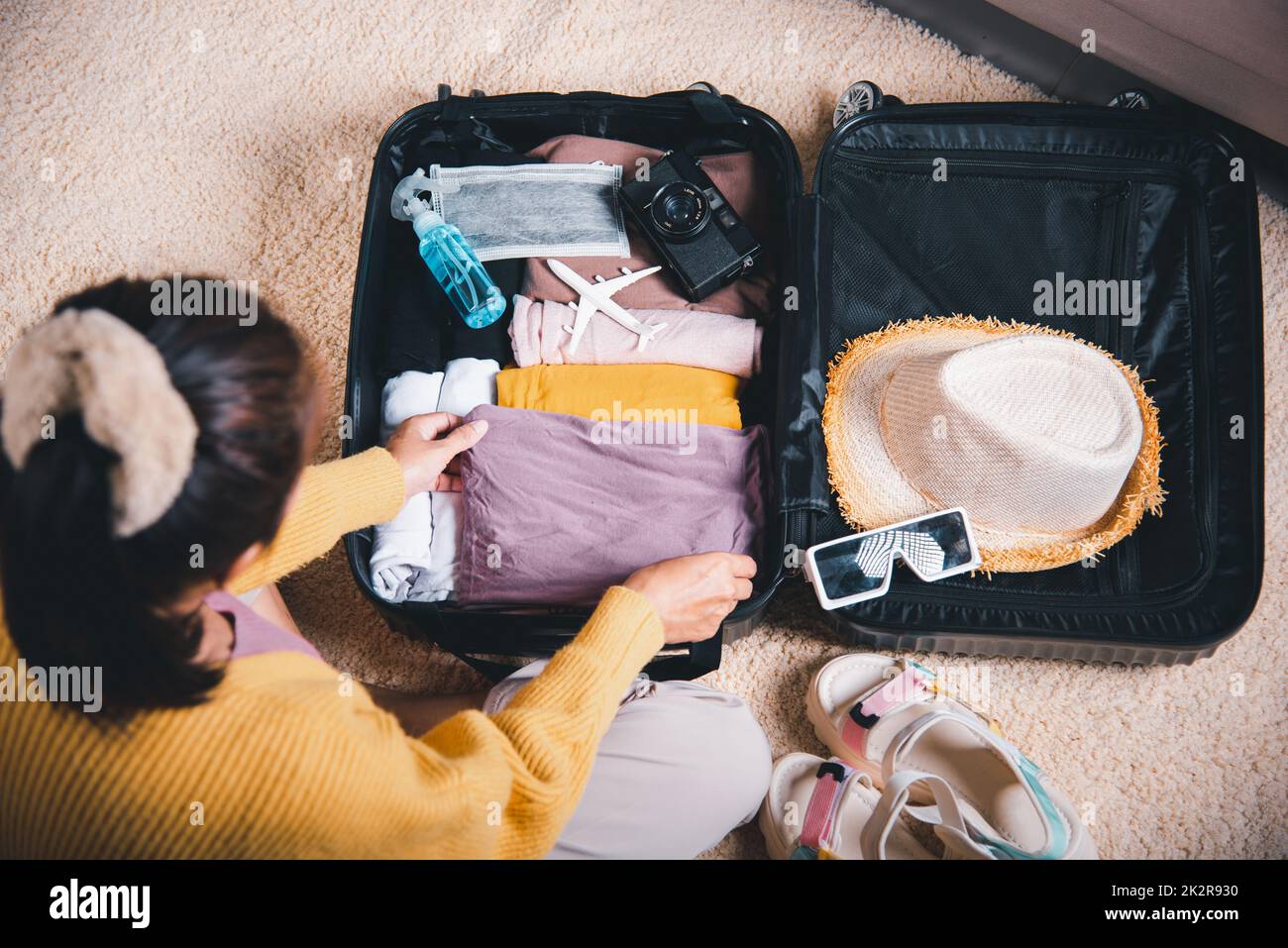 Donna che incolli i vestiti nei bagagli per un nuovo viaggio Foto Stock