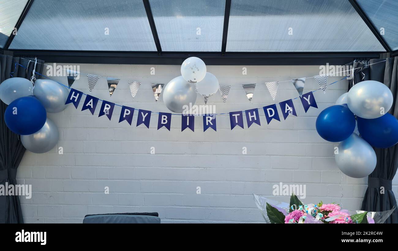 Buon compleanno decorazione appende di fronte a una parete bianca Foto Stock