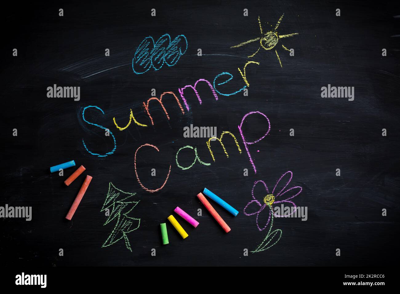 Testo campo estivo scritto su lavagna nera, con bastoncini di gesso di diversi colori Foto Stock