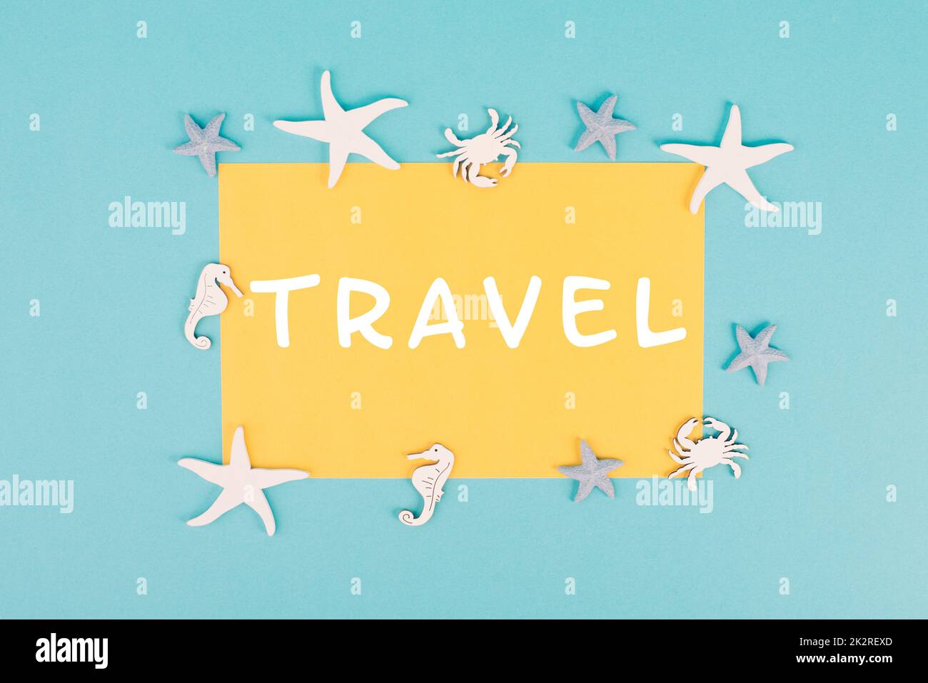 La parola viaggio è in piedi su una carta di colore giallo, stelle del mare, cavallucci marini e granchio che puntano una cornice, vacanze estive, destinazione turistica Foto Stock