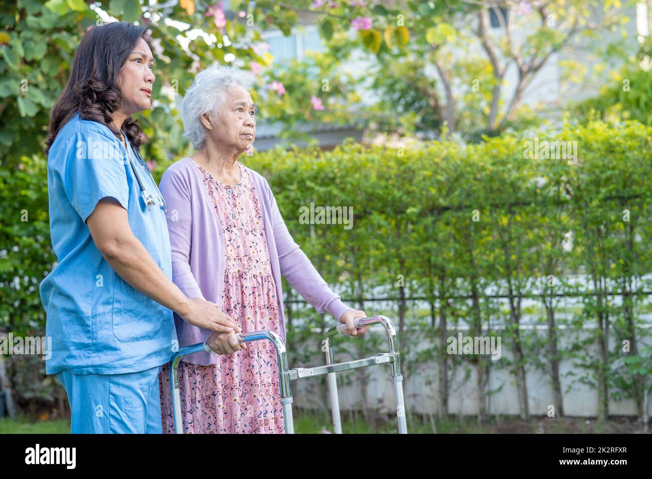 Aiuto del medico e cura Asian anziani o anziani donna vecchia uso walker con la salute forte mentre camminando al parco in felice vacanza fresca. Foto Stock
