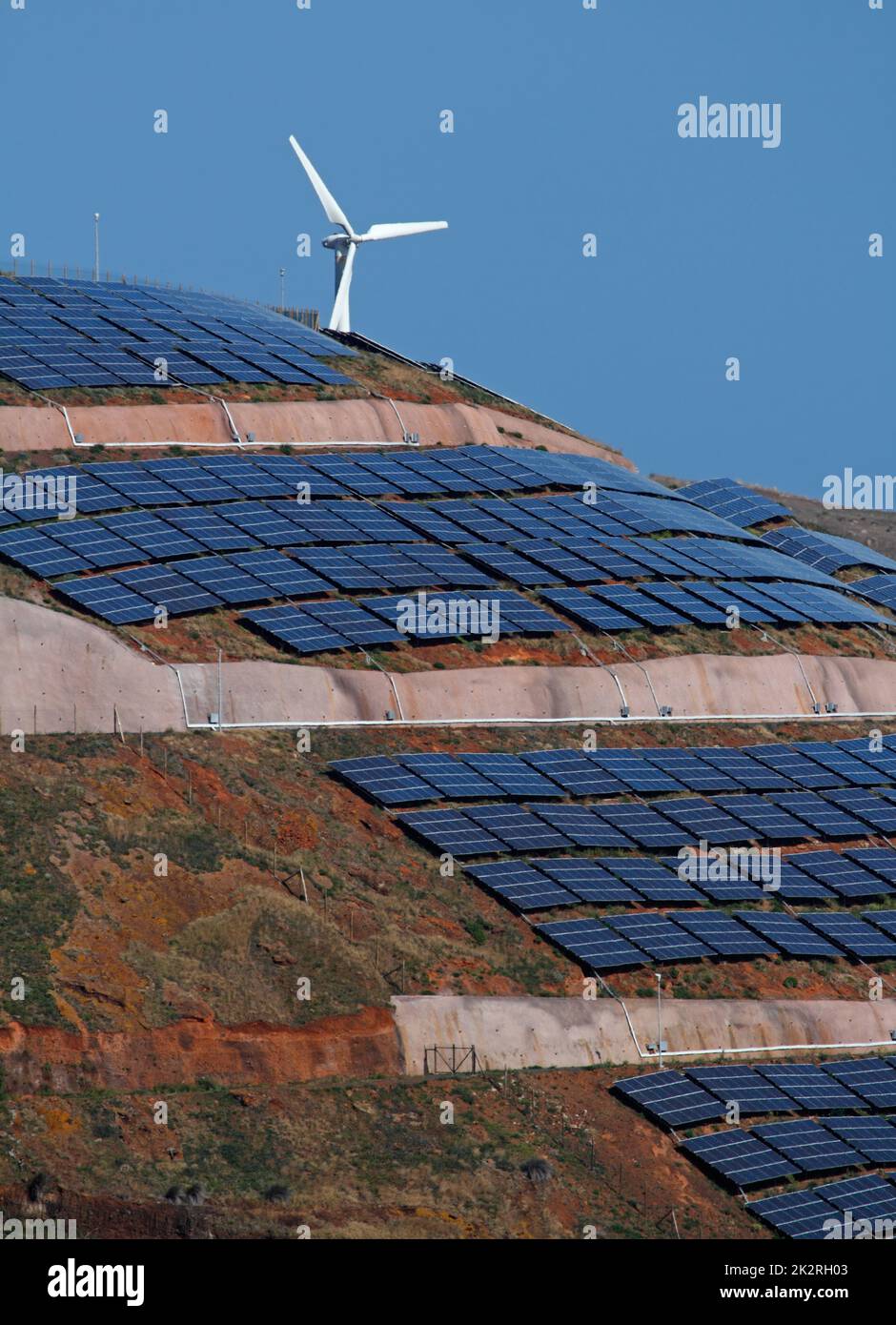 pannelli solari fotovoltaici e turbine eoliche che generano energia elettrica su colline e cielo blu. Ecologia verde natura concetto. Foto Stock