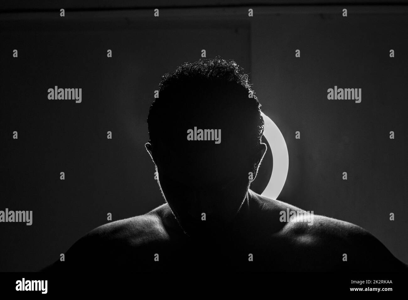 Silhouette delle spalle di un atletico di fronte a un tiro rotondo in scala di grigi e chiaro Foto Stock