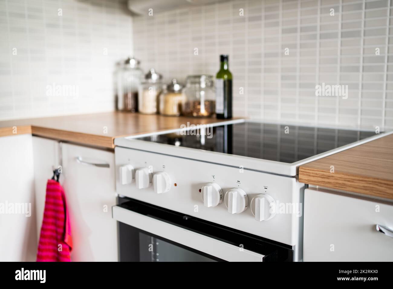 Cucina con piano cottura, forno e tavolo. Design di cabinet in una piccola casa. Fornello elettrico a induzione in ceramica. Decorazioni bianche scandinave contemporanee. Foto Stock