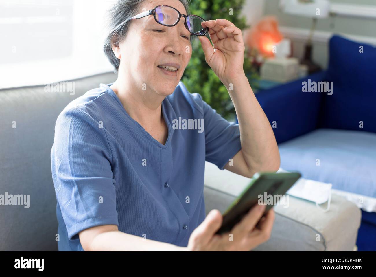 Donna anziana con occhiali, cercare di leggere messaggi sul telefono cellulare Foto Stock