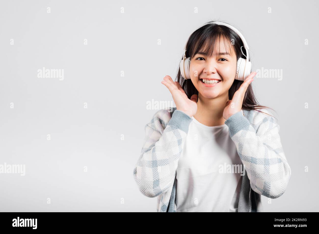 Donna emozionata sorridendo ascoltando la radio musicale con le cuffie bluetooth e tenendo in mano il telefono Foto Stock