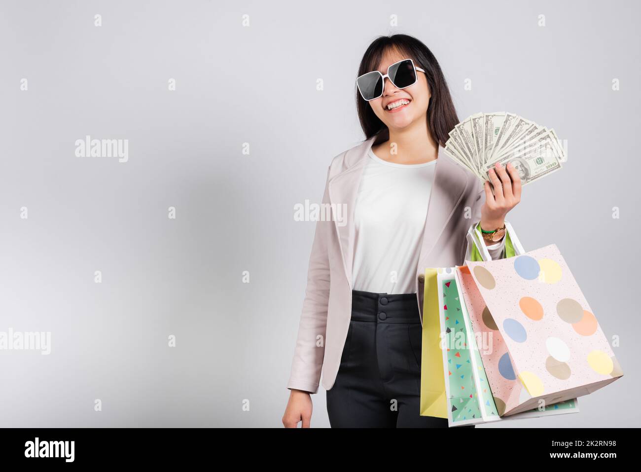 Donna con gli occhiali sicuro shopper sorridere tenendo in mano borse shopping online multicolore e banconote in dollari Foto Stock