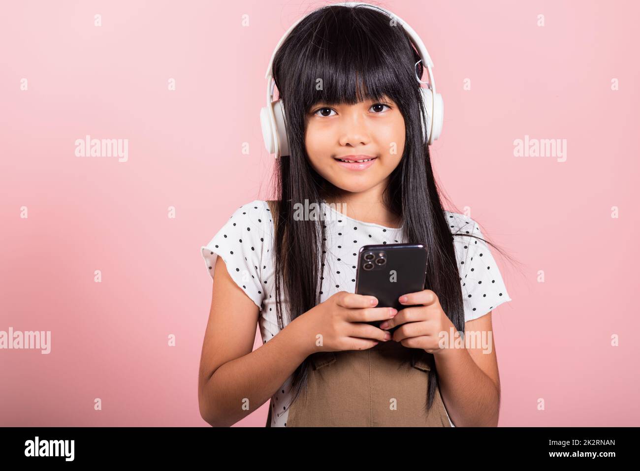 Bambino asiatico da 10 anni che ascolta la musica dal telefono cellulare indossare cuffie wireless Foto Stock