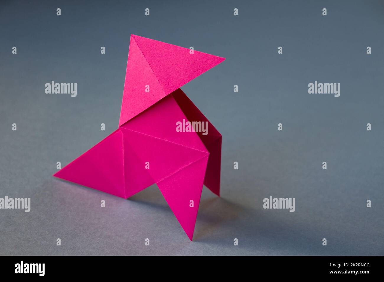 Carta rosa gallina origami isolato su uno sfondo grigio Foto Stock