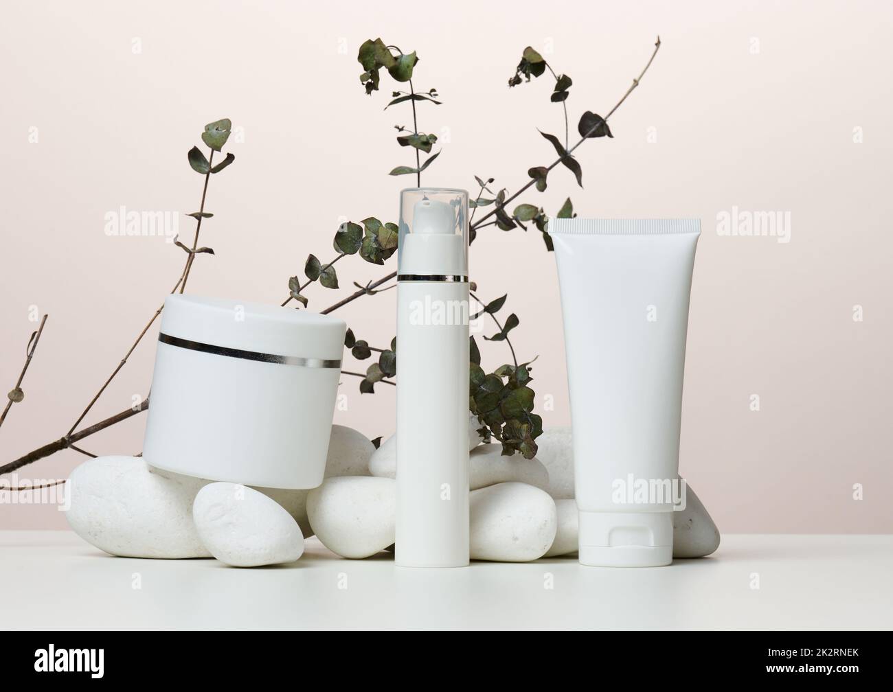 Vasetto, bottiglia e tubi di plastica bianca vuoti per cosmetici su sfondo beige. Foto Stock