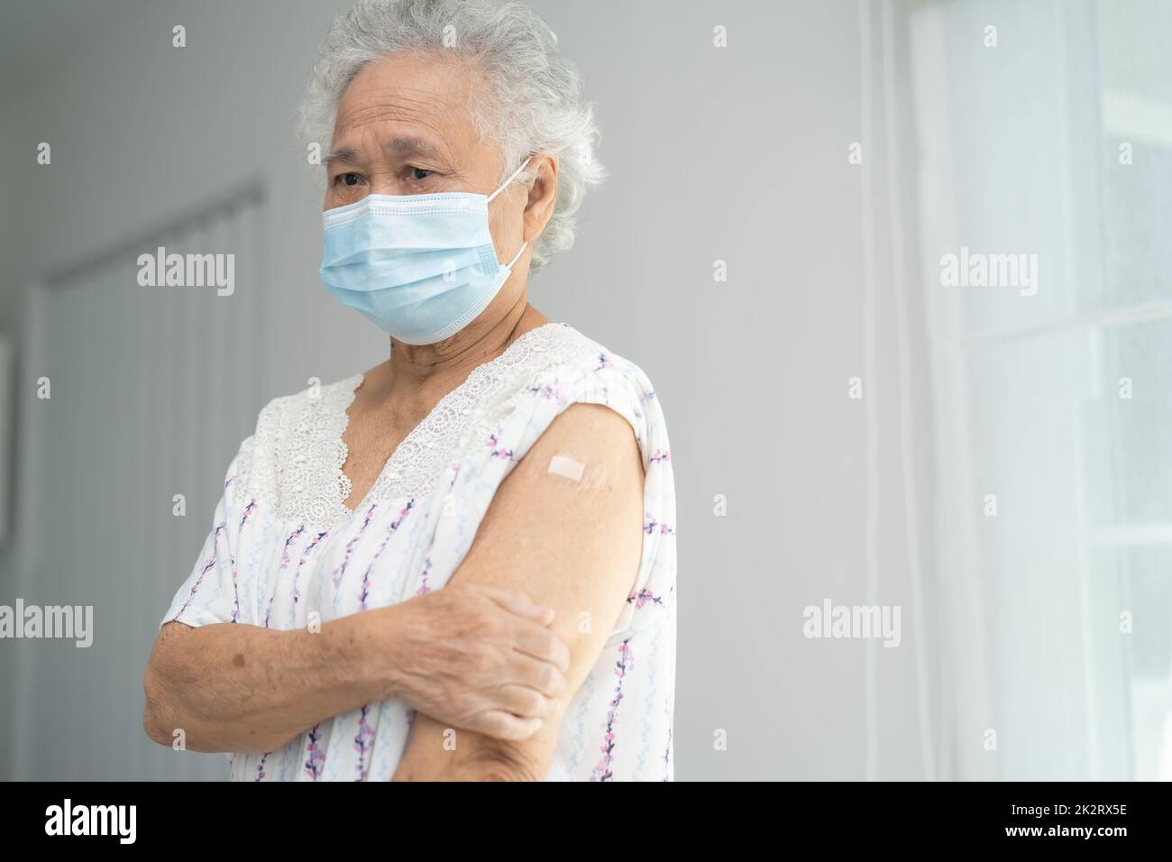 Anziana donna asiatica anziana che indossa la maschera per il viso che riceve covid-19 o il vaccino del coronavirus da parte del medico fare l'iniezione. Foto Stock