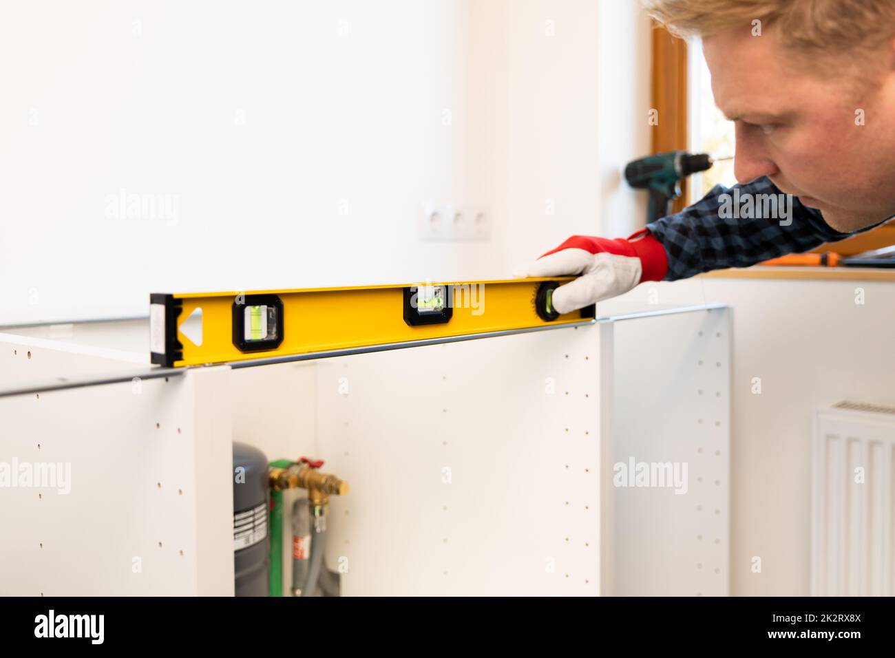 Miglioramento della casa. Handyman con livellatore installare nuovo piano di lavoro in cucina recentemente ristrutturato. Foto Stock