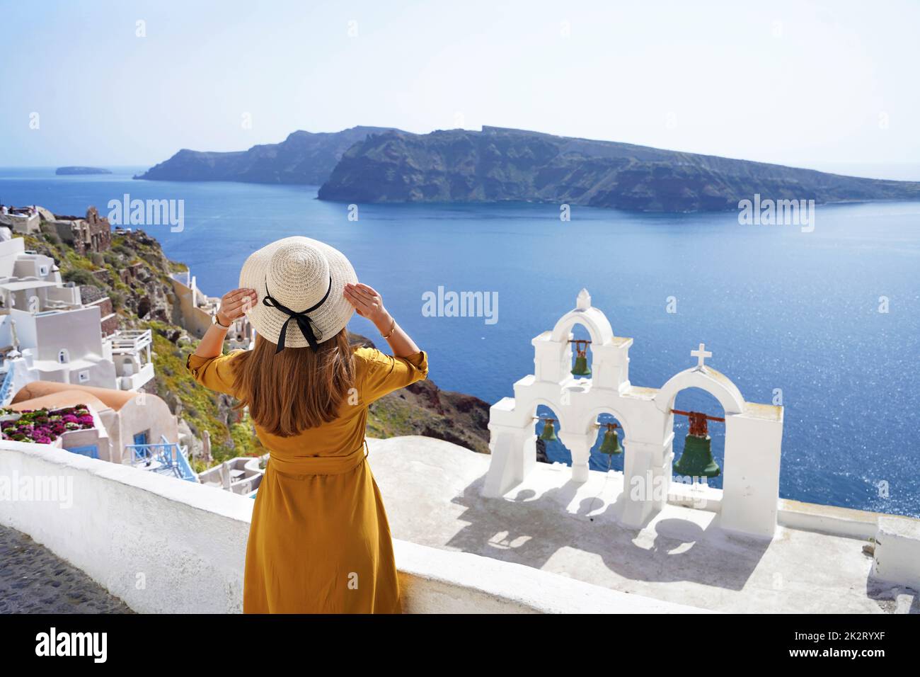 Turismo in Europa. Vista posteriore della giovane donna che guarda un paesaggio mozzafiato nel pittoresco villaggio di Oia, Santorini Island, Grecia. Foto Stock