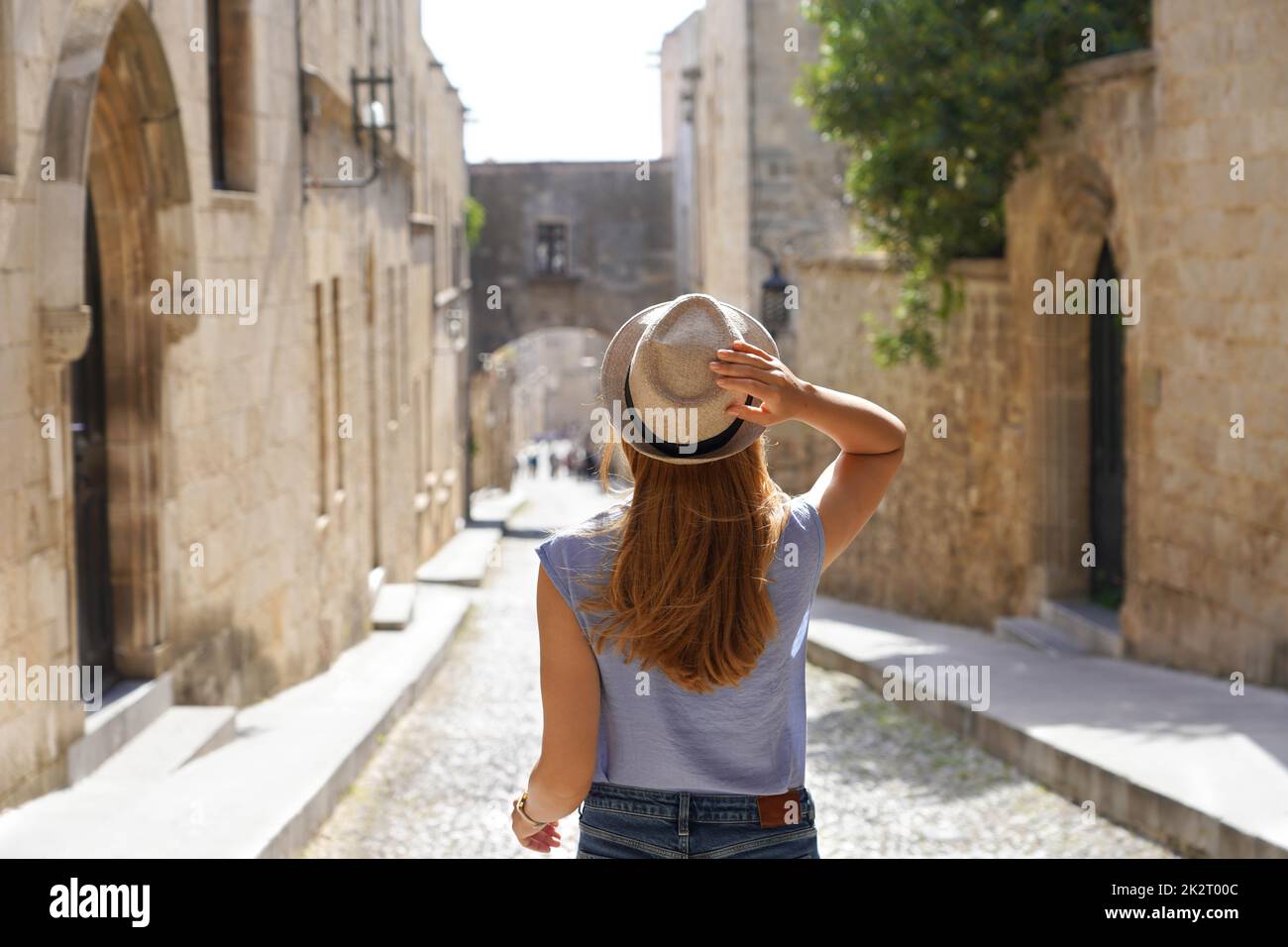 Turismo a Rodi, Grecia. Vista posteriore della ragazza viaggiatore scende lungo la strada dei Cavalieri della città di Rodi, Grecia. Giovane donna in viaggio nell'Europa meridionale. Foto Stock