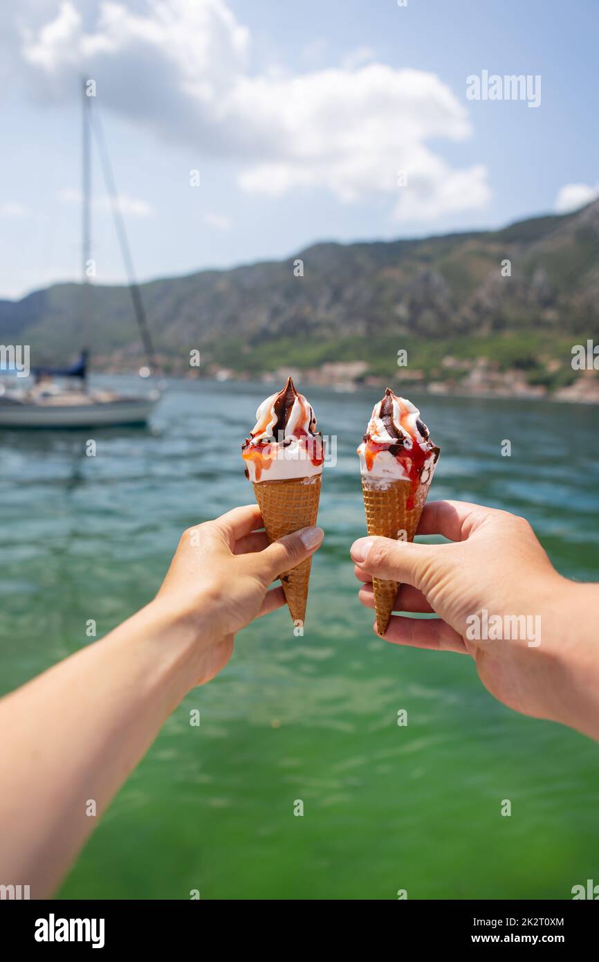 Molto bella passeggiata della baia di Cattaro, Montenegro. Coppia amatissima che tiene un gelato colorato sullo sfondo della baia di Cattaro. Foto Stock