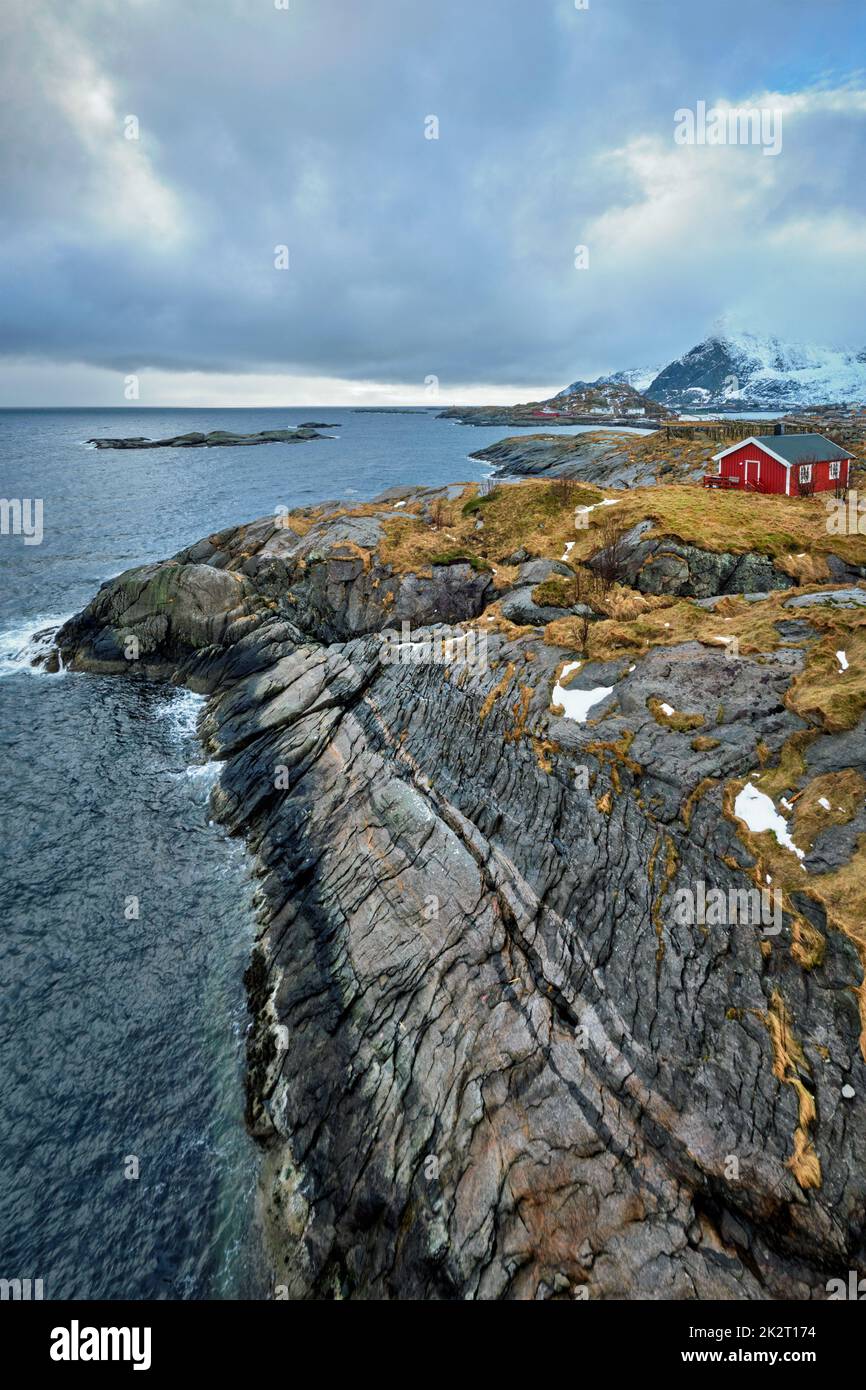 Clif con tradizionale rosso rorbu casa sulle Isole Lofoten in Norvegia Foto Stock