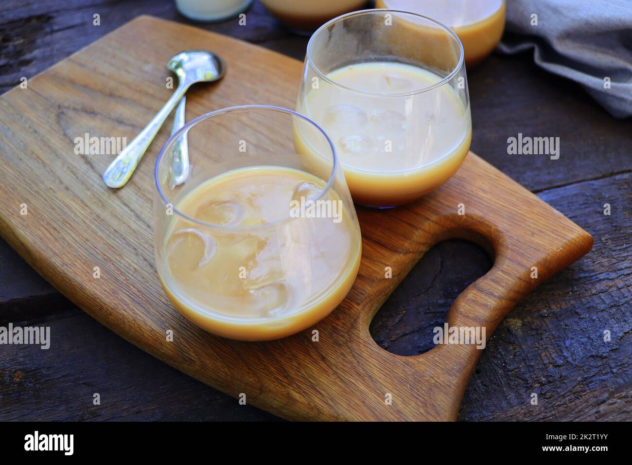 Caffè ghiacciato con bicchieri da latte montati su un rustico tavolo in legno, fuoco selettivo Foto Stock