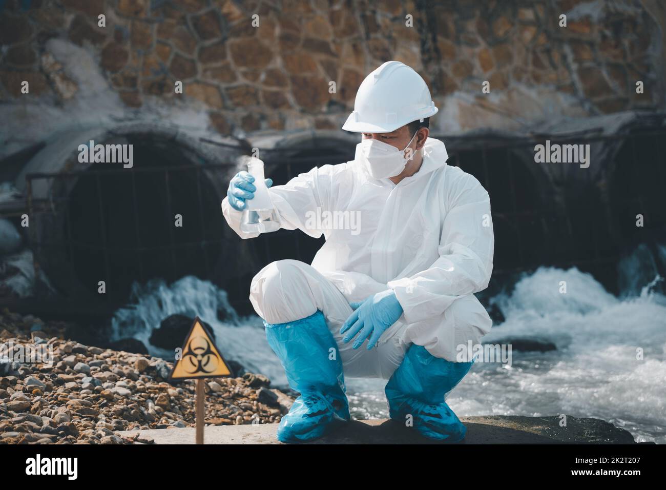Ecologo che campiona l'acqua dal fiume con vetro per provette e ha fumo bianco Foto Stock