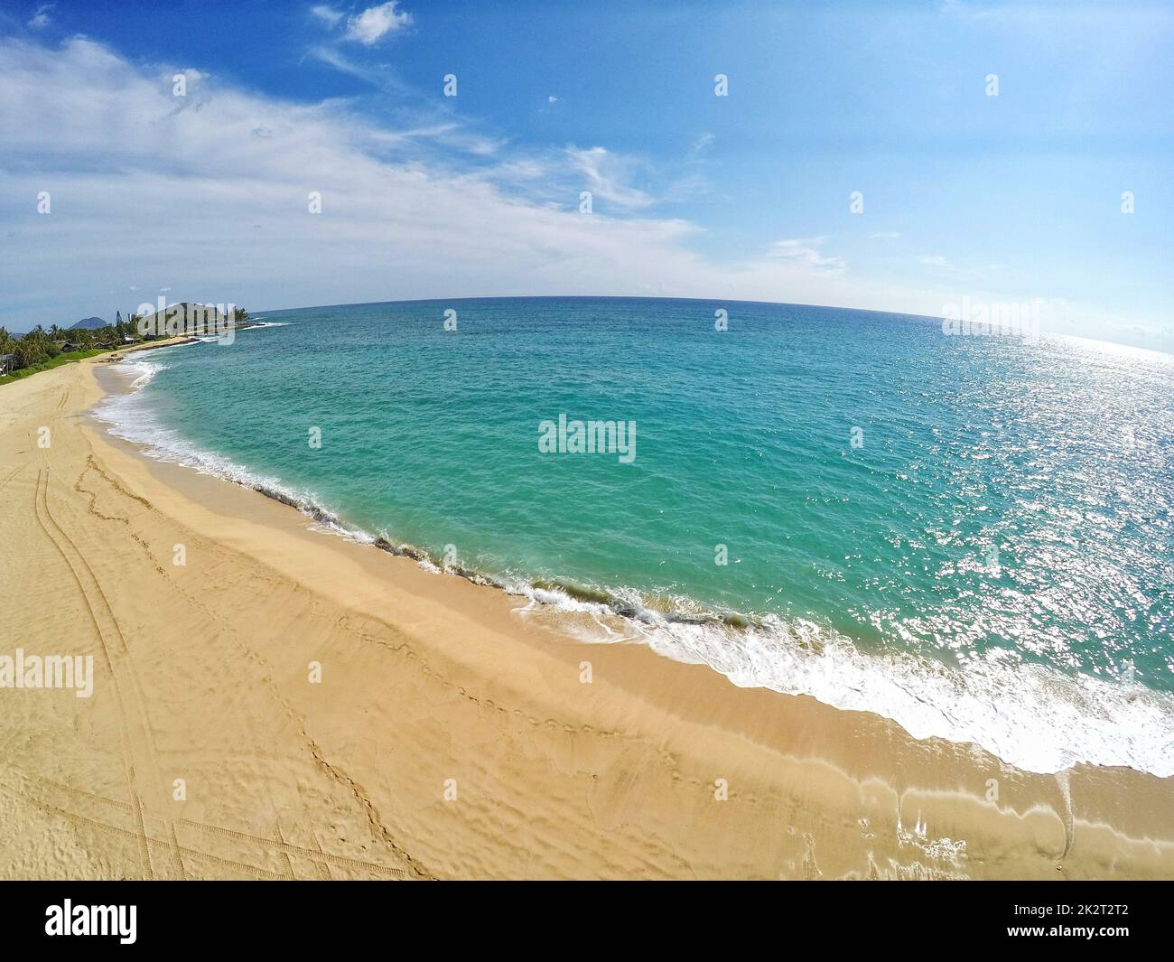 Un mare contro una spiaggia sabbiosa in una giornata di sole girato in obiettivo occhio di pesce Foto Stock