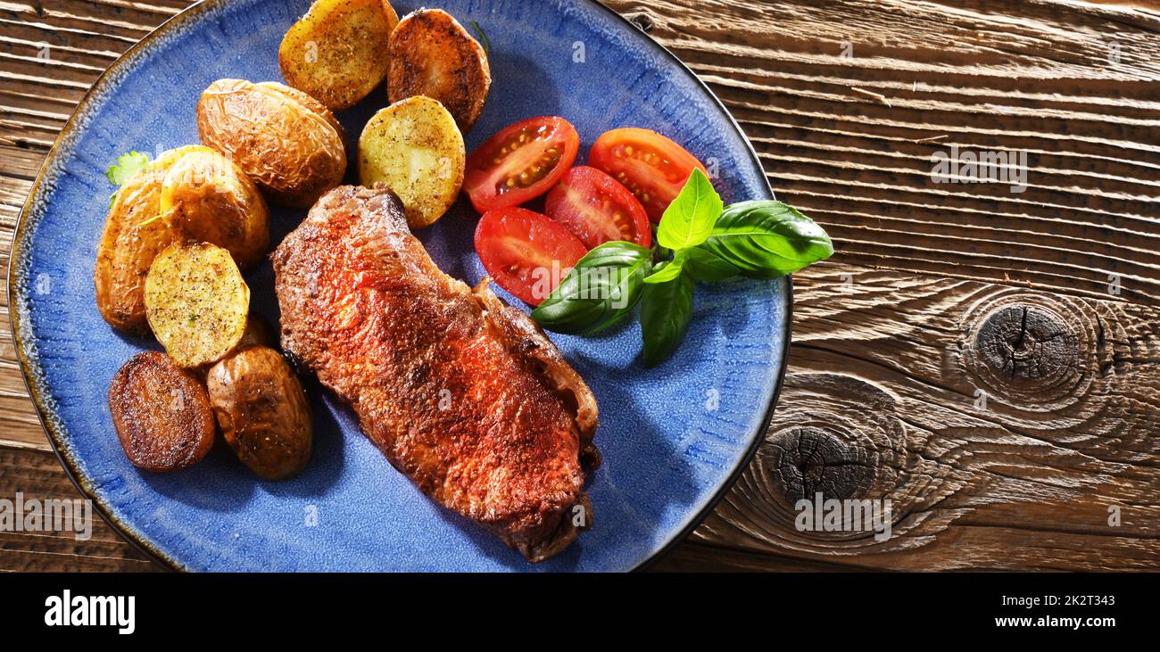 Bistecca di manzo in padella con patate fritte e pomodori ciliegini Foto Stock