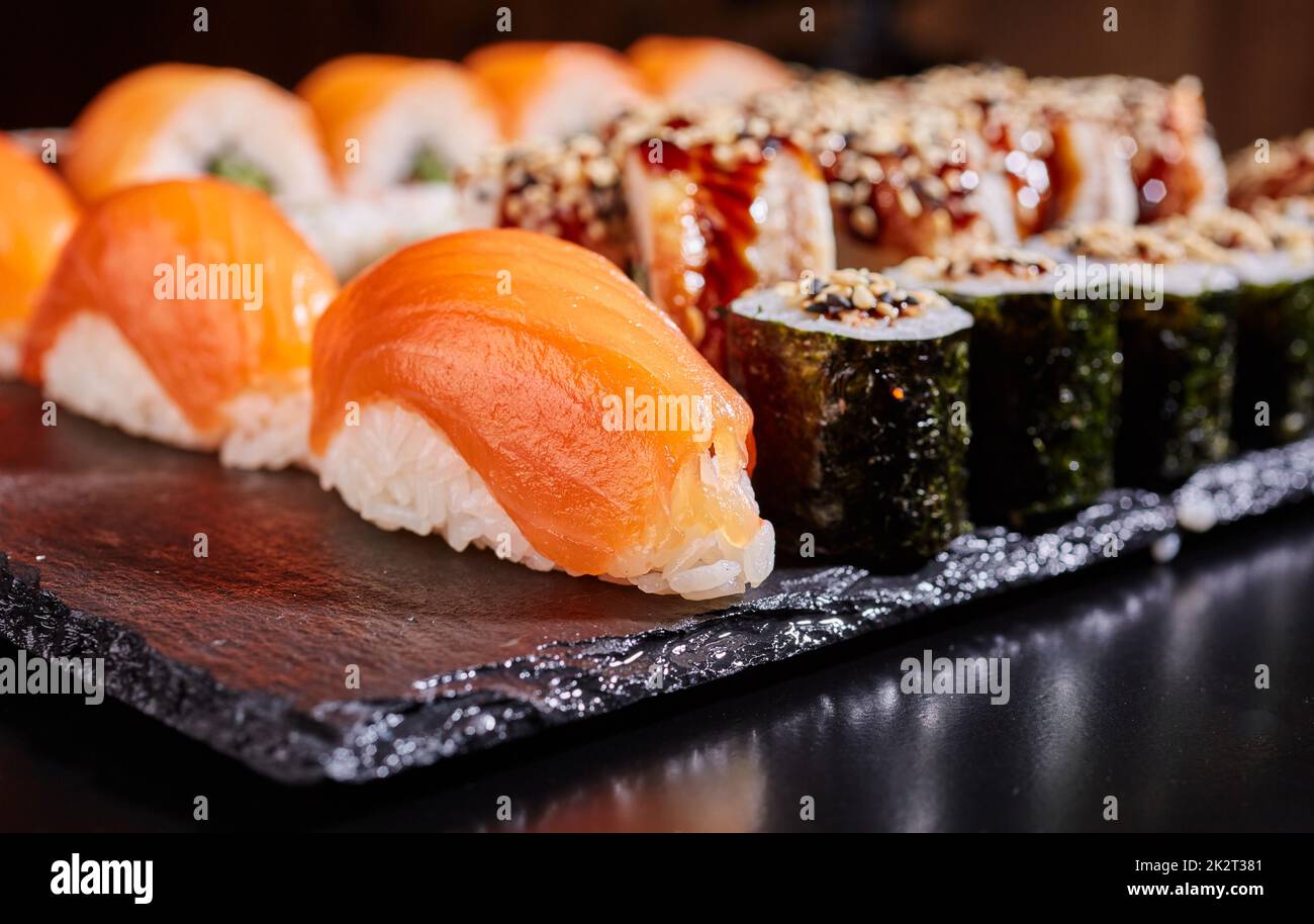 Sushi tradizionale sashimi con salmone su una tavola piatta nera. Foto Stock