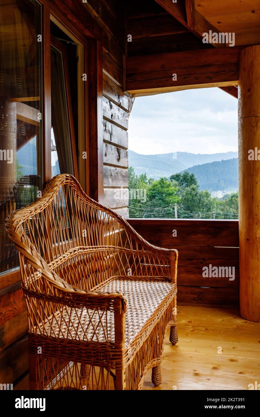 Terrazza con panca di vimini su balcone in legno con vista sulle montagne. Foto Stock