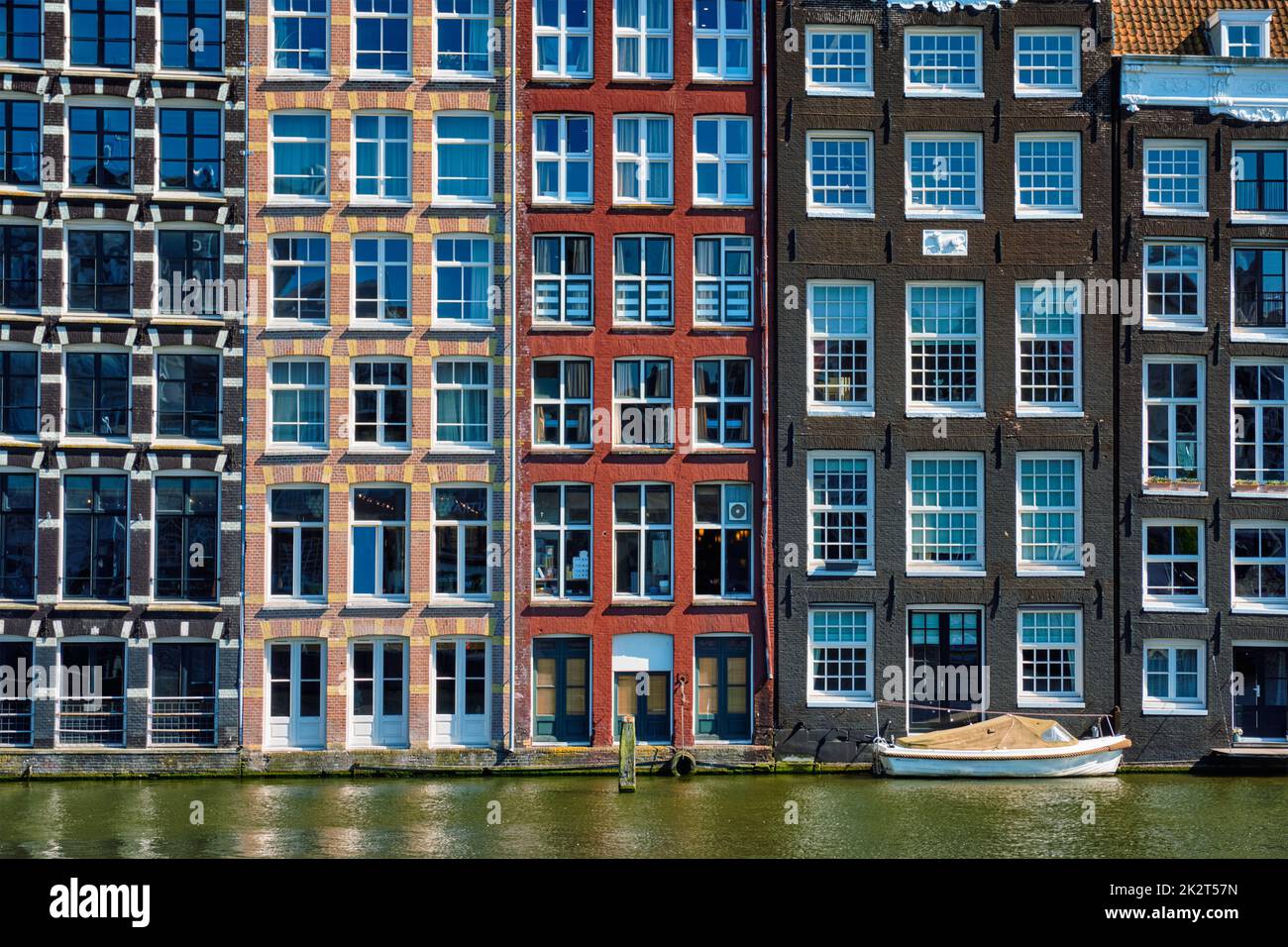 Case e barca sul canale di Amsterdam Damrak con la riflessione. Ams Foto Stock